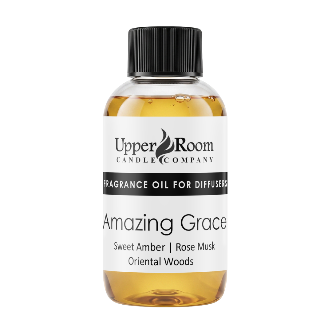 A bottle of Upper Room Candle Company 'Amazing Grace' fragrance oil for diffusers, featuring a white label with black text and a black ribbed cap, filled with amber-colored liquid, on a solid white background.