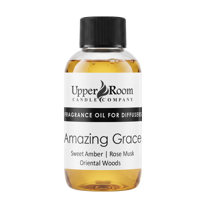 A bottle of Upper Room Candle Company 'Amazing Grace' fragrance oil for diffusers, featuring a white label with black text and a black ribbed cap, filled with amber-colored liquid, on a solid white background.