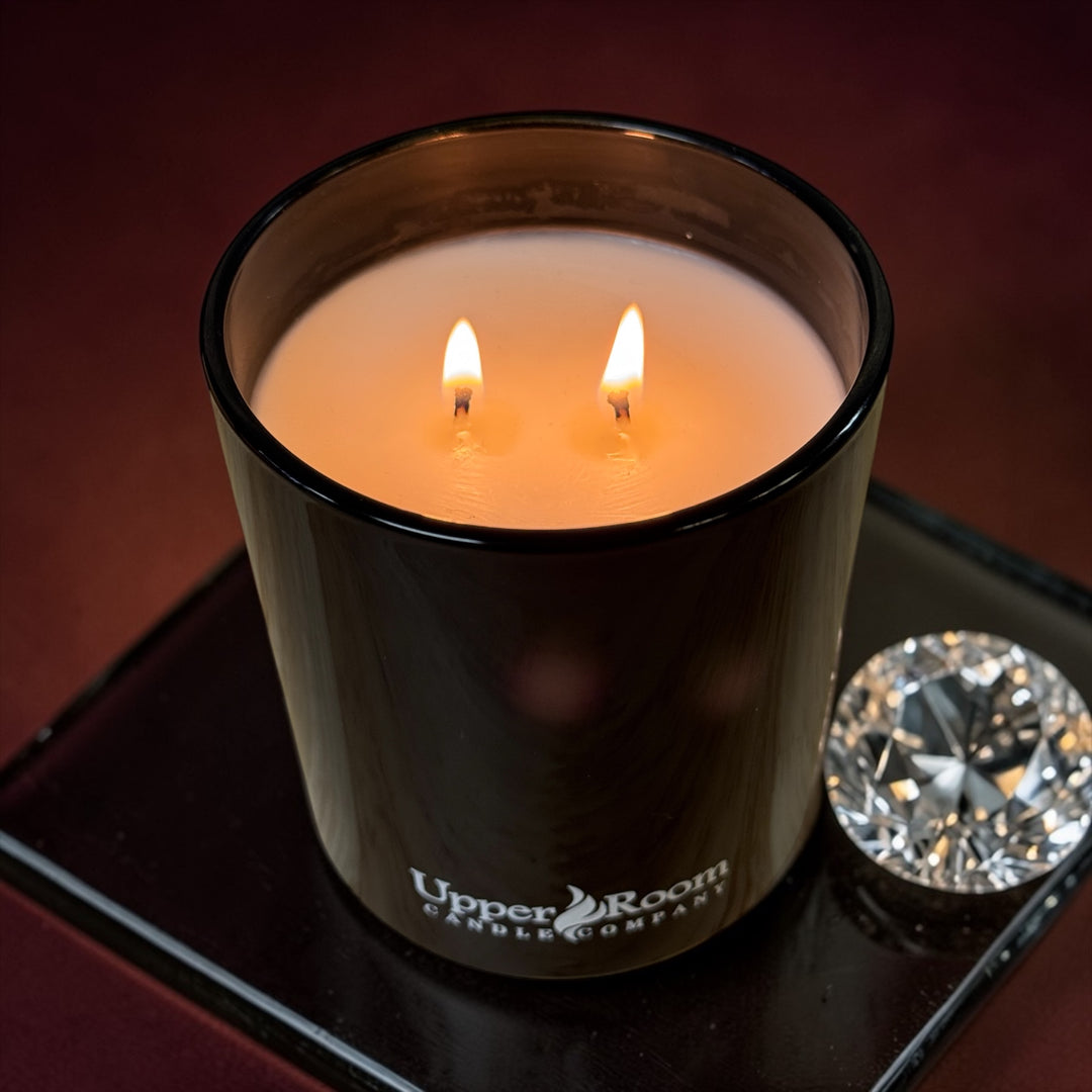LA BAIE ROUGE Candle double wick black jar, upper room candle company, on black tile, large diamond next to it