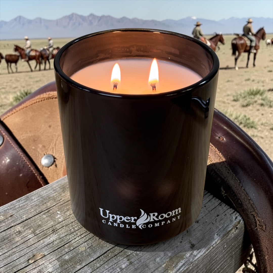 Rodeo days candle in a double wick black jar from upper room candle company with horses and cows in the background