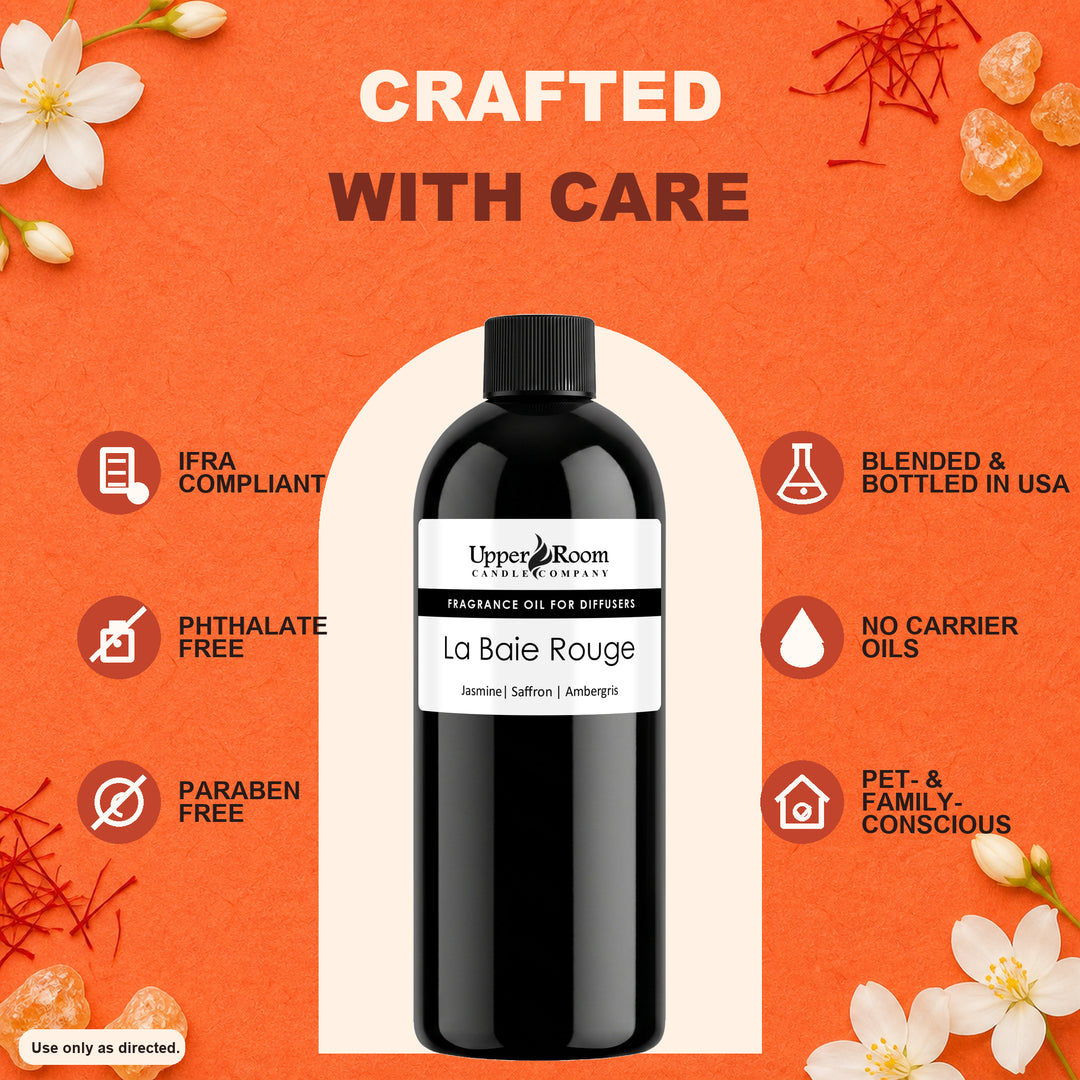 A bottle of Upper Room Candle Co. La Baie Rouge fragrance oil for diffusers, presented on a textured orange background with decorative white flowers and text highlighting product features.
